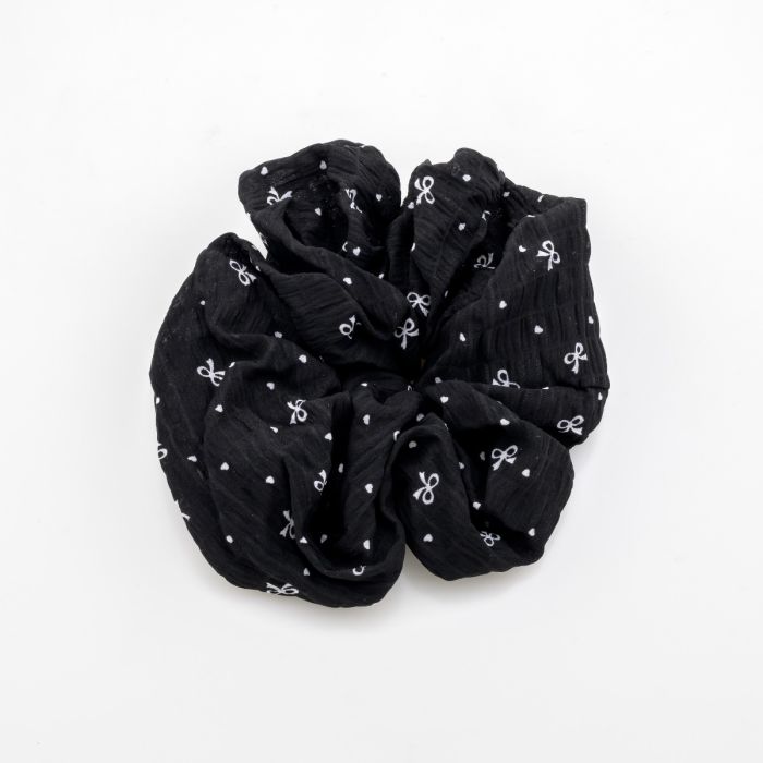Υφασμάτινο scrunchie μαλλιών με ανάγλυφη υφή, διακοσμημένο με μικρούς φιόγκους και πουά, διαθέσιμο σε μαύρο και κρεμ χρώμα.