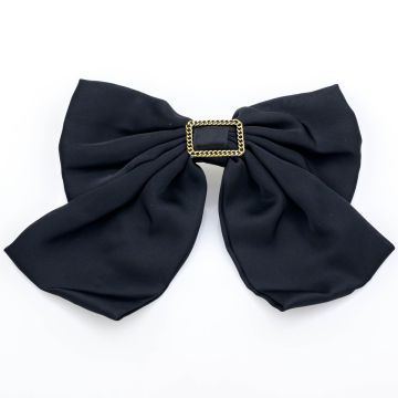 Μαύρη μπαρέτα φιόγκο με μια διακοσμητική χρυσή αγκράφα και αλυσίδα.